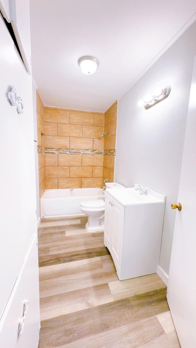 full bathroom featuring hardwood / wood-style flooring, vanity, tiled shower / bath combo, and toilet