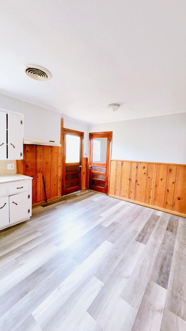 interior space with wooden walls and light hardwood / wood-style flooring