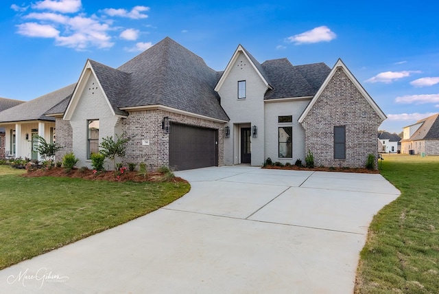 view of front of house with a front yard, driveway, roof with shingles, a garage, and brick siding