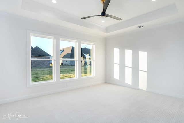 unfurnished room featuring light colored carpet, a raised ceiling, and baseboards