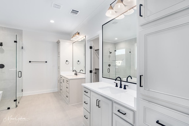 bathroom featuring visible vents, a shower stall, two vanities, and a sink