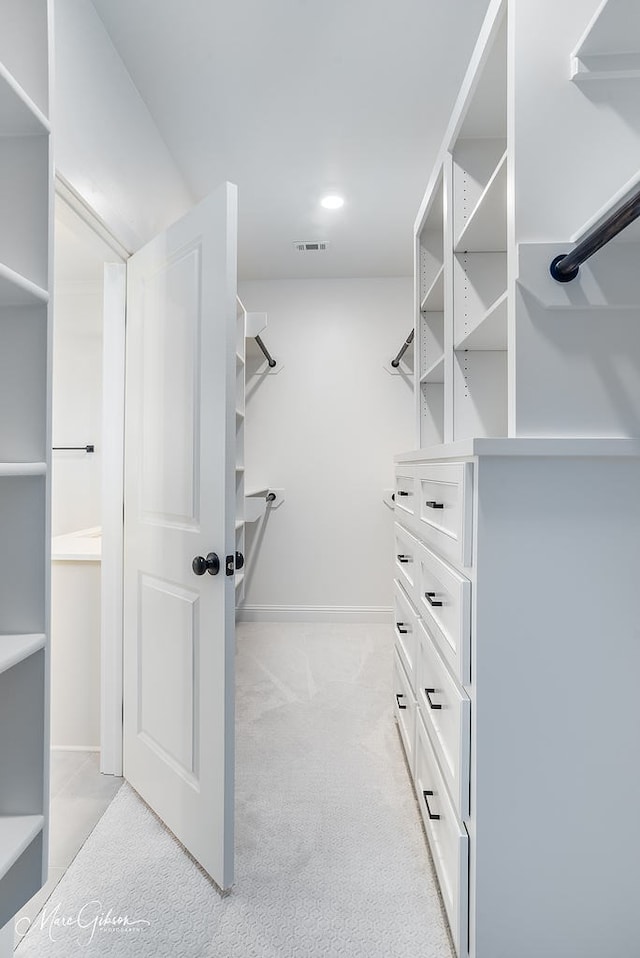 spacious closet featuring light colored carpet and visible vents