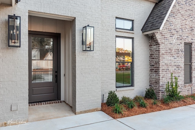 property entrance with brick siding and roof with shingles