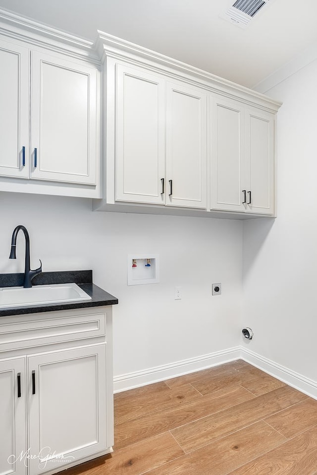 clothes washing area with washer hookup, light wood-style floors, visible vents, and a sink