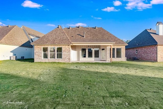 back of house with a lawn, a patio, roof with shingles, brick siding, and ceiling fan