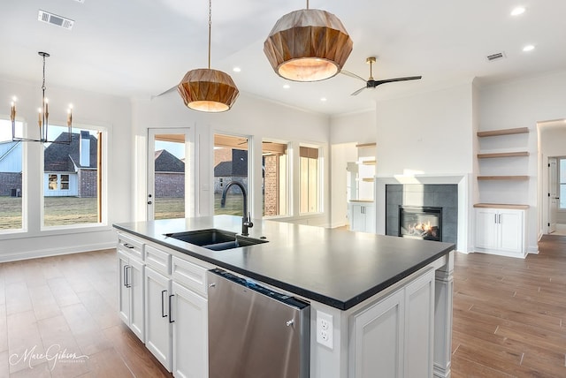 kitchen with dark countertops, visible vents, a tiled fireplace, dishwasher, and a sink