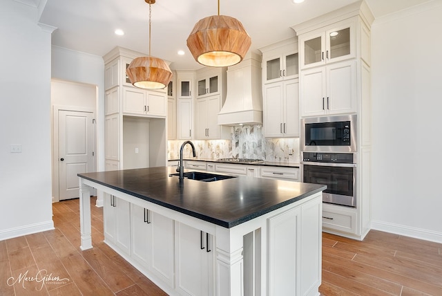 kitchen with custom range hood, a sink, backsplash, dark countertops, and appliances with stainless steel finishes