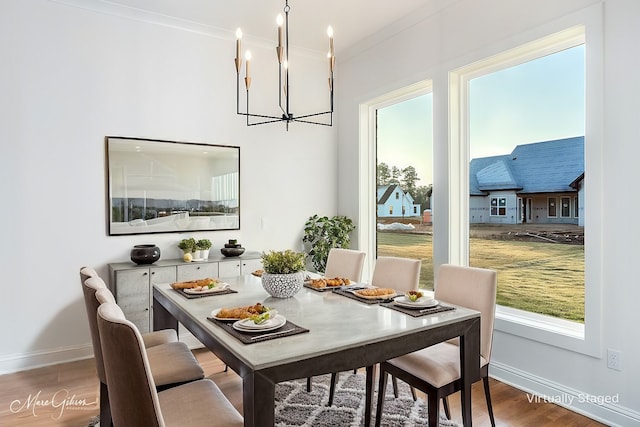 dining room featuring an inviting chandelier, wood finished floors, baseboards, and ornamental molding