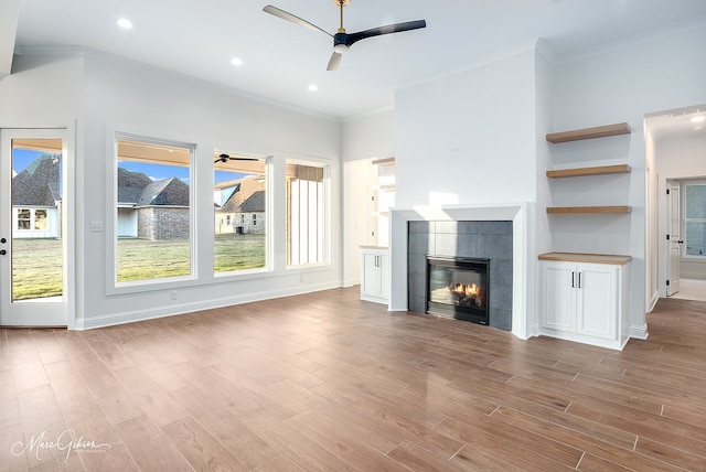 unfurnished living room with a wealth of natural light, wood finished floors, a ceiling fan, and a tile fireplace