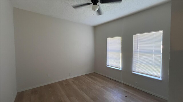 empty room with a textured ceiling, light wood-type flooring, and ceiling fan