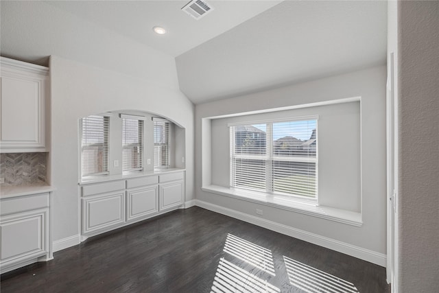 unfurnished dining area featuring lofted ceiling and dark hardwood / wood-style floors