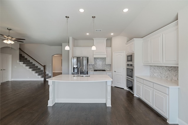 kitchen with pendant lighting, stainless steel appliances, a kitchen island with sink, and white cabinets