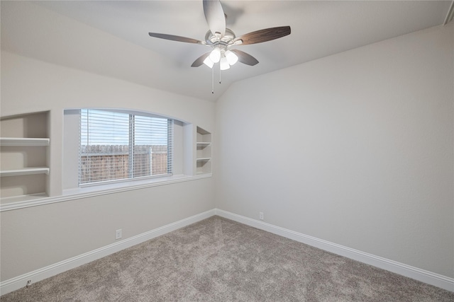 spare room with built in shelves, vaulted ceiling, ceiling fan, and carpet