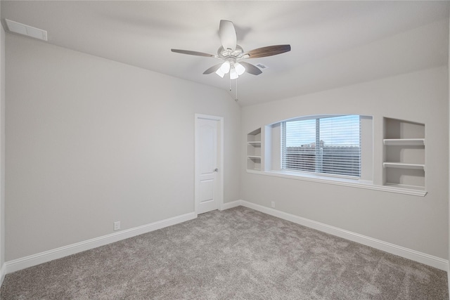 empty room with built in shelves, ceiling fan, vaulted ceiling, and light carpet