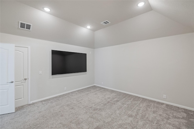 carpeted spare room featuring vaulted ceiling