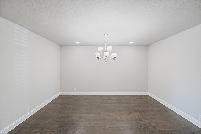 unfurnished dining area featuring dark hardwood / wood-style floors, a notable chandelier, and a textured ceiling