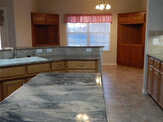 kitchen featuring tasteful backsplash, sink, pendant lighting, a chandelier, and light tile patterned flooring