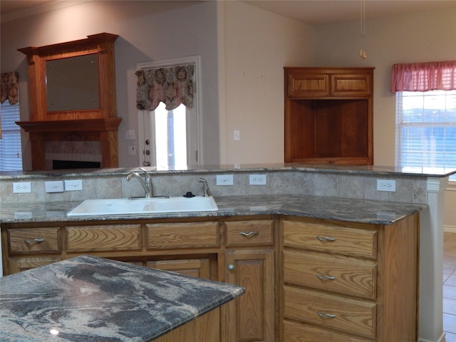 kitchen with sink, dark stone counters, and ornamental molding