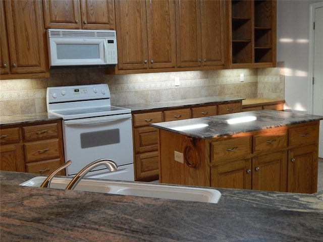 kitchen with a center island, white appliances, dark stone counters, sink, and tasteful backsplash