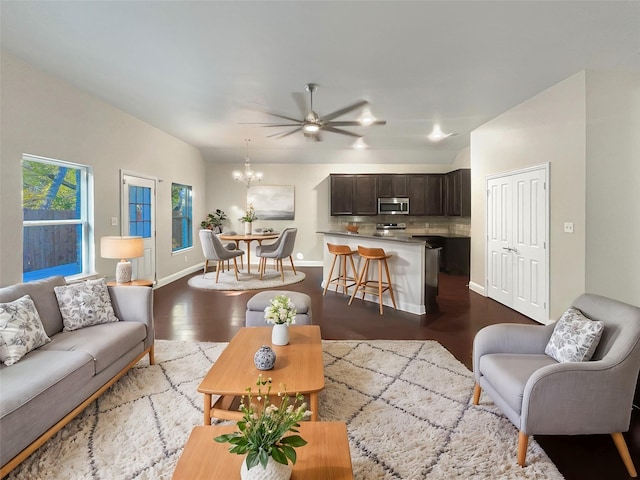 living room with ceiling fan with notable chandelier and light hardwood / wood-style flooring