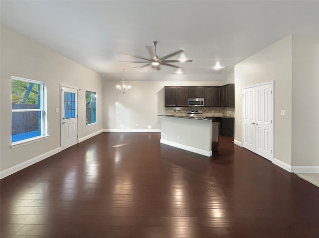 unfurnished living room featuring ceiling fan with notable chandelier and dark hardwood / wood-style floors