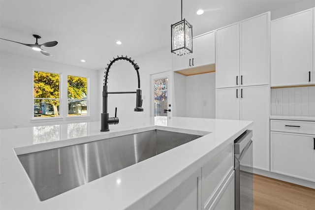 kitchen featuring white cabinets, pendant lighting, light wood-type flooring, and sink