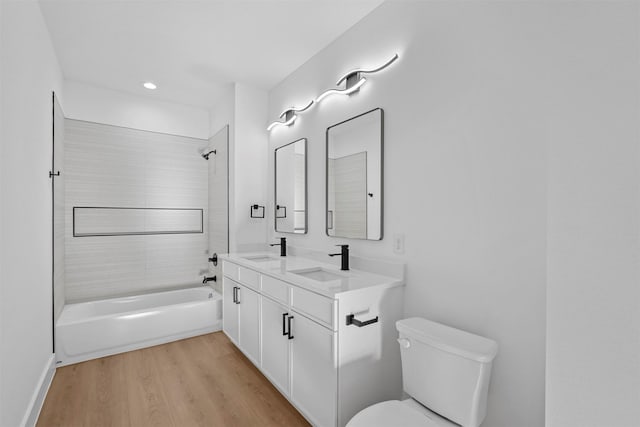 full bathroom featuring vanity, hardwood / wood-style floors, tiled shower / bath combo, and toilet