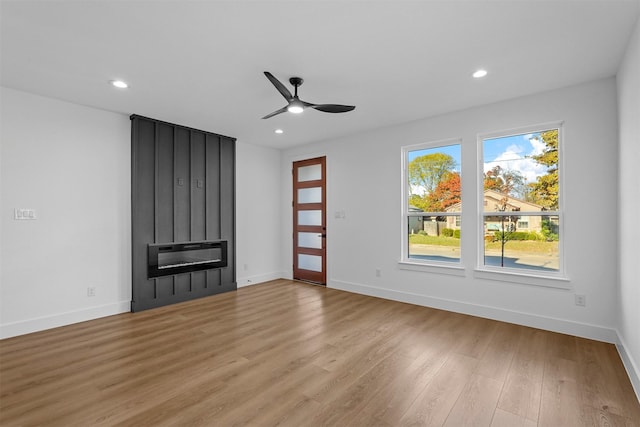 unfurnished living room with a large fireplace, ceiling fan, and light hardwood / wood-style floors