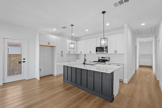 kitchen with sink, decorative light fixtures, a center island with sink, white cabinets, and appliances with stainless steel finishes