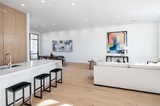 living room with sink and light hardwood / wood-style flooring