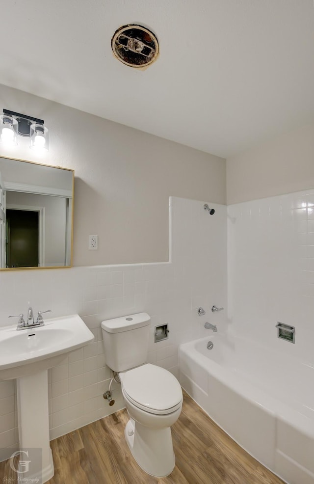 full bathroom with sink, hardwood / wood-style floors, toilet, shower / bathing tub combination, and tile walls