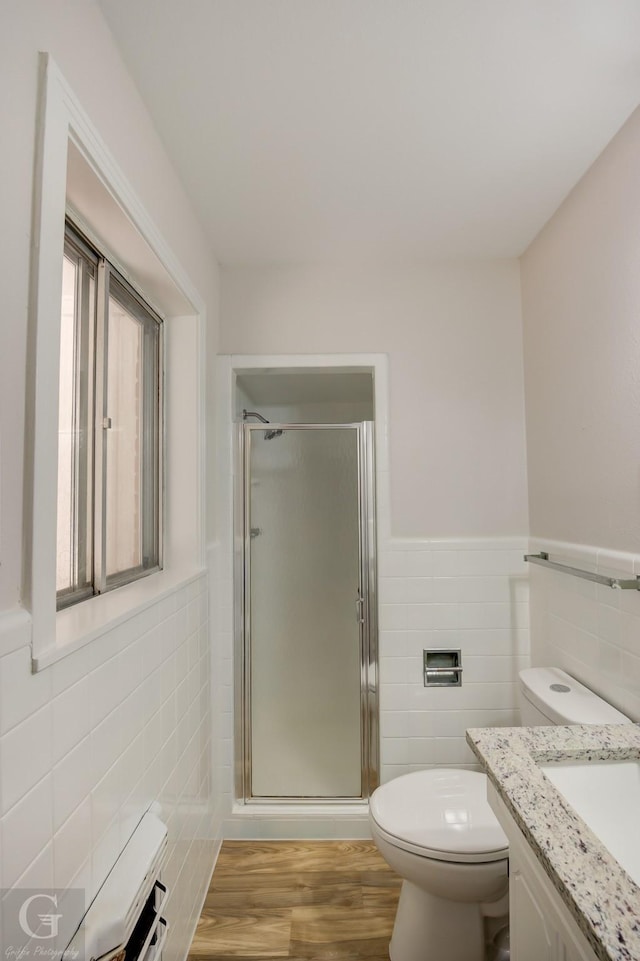 bathroom featuring hardwood / wood-style flooring, toilet, tile walls, and a shower with shower door