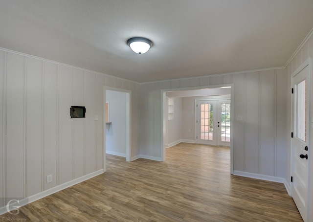 empty room featuring french doors, wood-type flooring, and ornamental molding