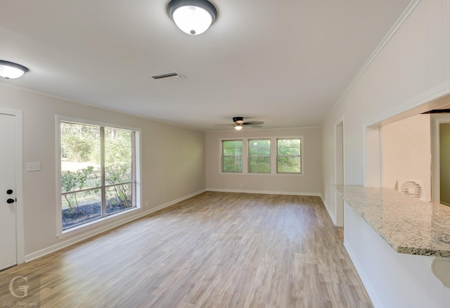 unfurnished living room with ceiling fan, light wood-type flooring, crown molding, and a wealth of natural light