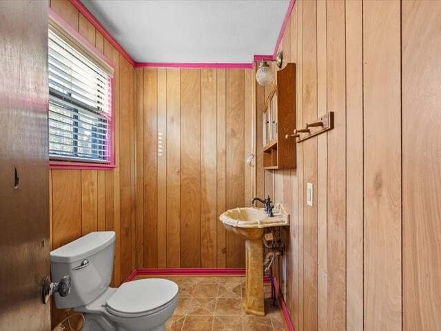 bathroom with tile patterned flooring, toilet, and wooden walls