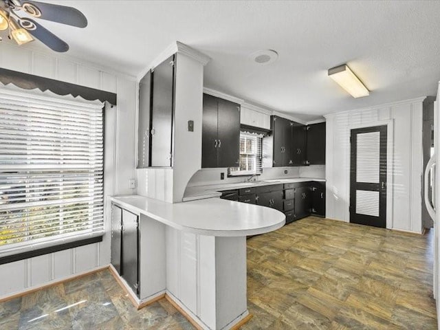 kitchen with kitchen peninsula, ceiling fan, sink, and a breakfast bar