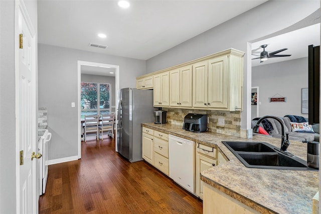 kitchen with sink, dark hardwood / wood-style flooring, backsplash, white dishwasher, and cream cabinetry