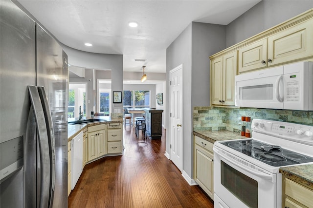 kitchen with backsplash, dark hardwood / wood-style flooring, white appliances, and cream cabinetry