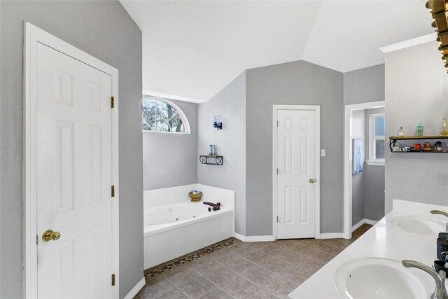 bathroom featuring a washtub, vanity, tile patterned floors, and lofted ceiling