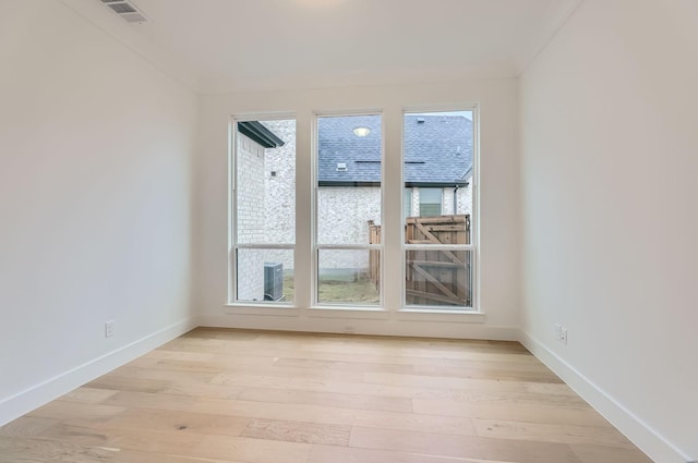 spare room featuring crown molding and light hardwood / wood-style flooring