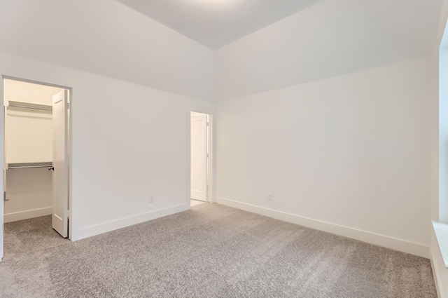 unfurnished bedroom with a walk in closet, light colored carpet, and a closet