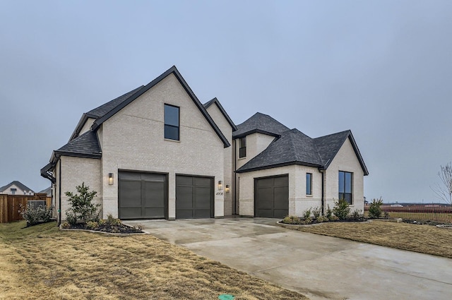 french country inspired facade featuring a garage and a front lawn