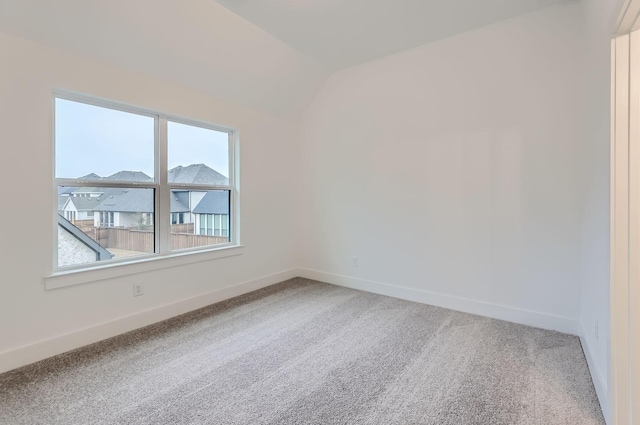 carpeted spare room with lofted ceiling