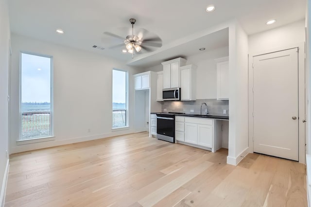 kitchen featuring white cabinetry, appliances with stainless steel finishes, light hardwood / wood-style floors, and backsplash