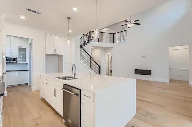 kitchen featuring sink, hanging light fixtures, stainless steel appliances, a kitchen island with sink, and white cabinets