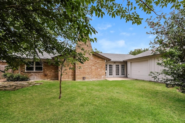 rear view of property with a lawn, french doors, and a garage