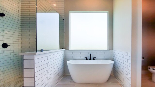 bathroom featuring tile walls, tile patterned flooring, shower with separate bathtub, and toilet