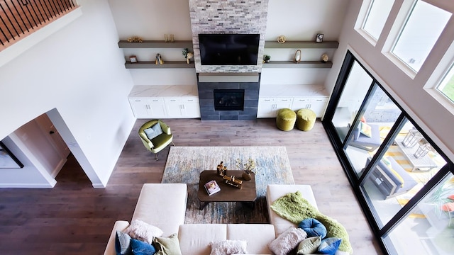 living room featuring a tile fireplace, a towering ceiling, and hardwood / wood-style floors