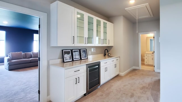 kitchen featuring white cabinets, light colored carpet, and wine cooler