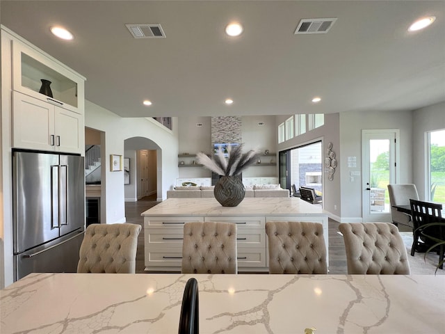 kitchen featuring white cabinets, stainless steel refrigerator, and light stone countertops